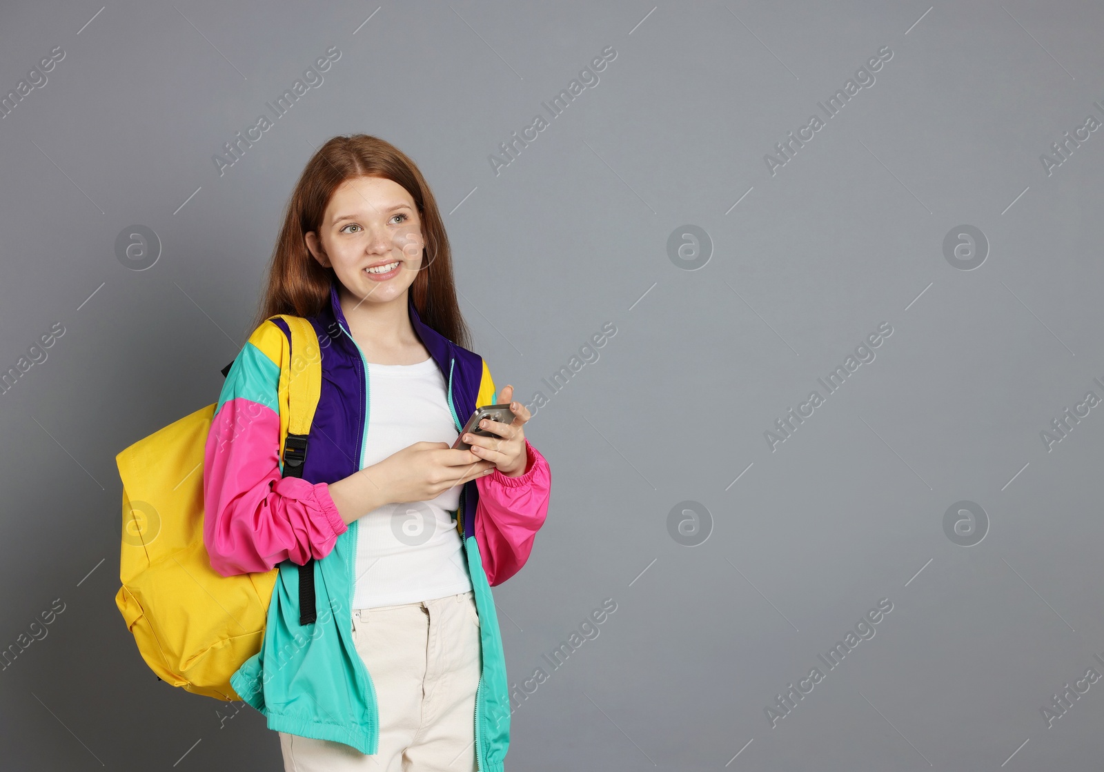 Teenage girl with smartphone on grey background. Space for text Photo of Teenage girl with smartphone on grey background. Space for text