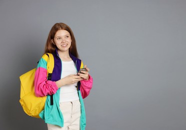 Photo of Teenage girl with smartphone on grey background. Space for text