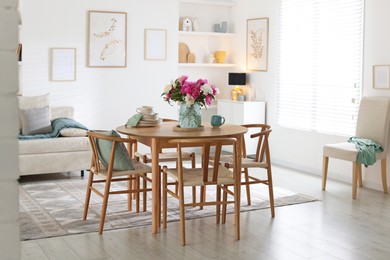 Photo of Dining table with beautiful flowers and dishware in room. Interior design