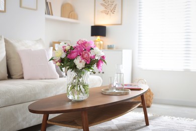 Photo of Bouquet of beautiful peonies and water on coffee table indoors, space for text. Interior design