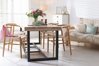 Photo of Dining table with beautiful flowers and dishware in room. Interior design