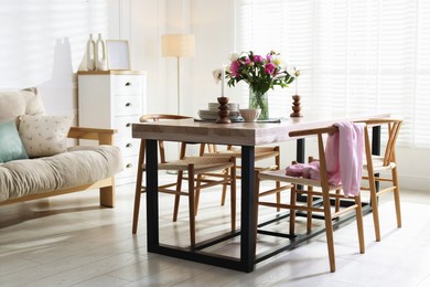 Photo of Dining table with beautiful flowers and dishware in room. Interior design