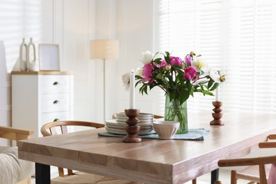 Photo of Dining table with beautiful flowers and dishware in room. Interior design