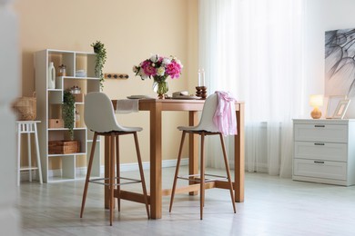 Photo of Beautiful table setting with bouquet of peonies in dining room. Interior design