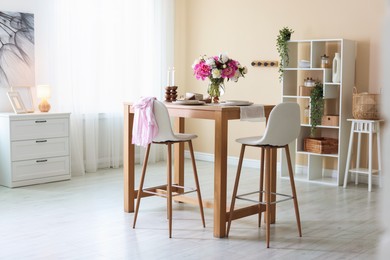Photo of Beautiful table setting with bouquet of peonies in dining room. Interior design