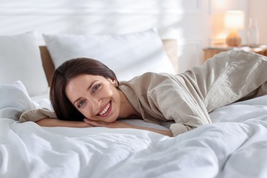Photo of Woman lying on bed with soft mattress at home