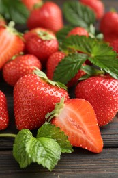 Photo of Fresh ripe strawberries and leaves on black wooden table, closeup