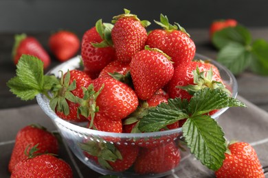 Photo of Fresh ripe strawberries and leaves in container on table, closeup