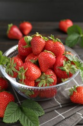 Photo of Fresh ripe strawberries and leaves in container on table, closeup