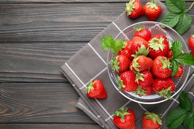 Photo of Fresh ripe strawberries and leaves in container on black wooden table, flat lay. Space for text