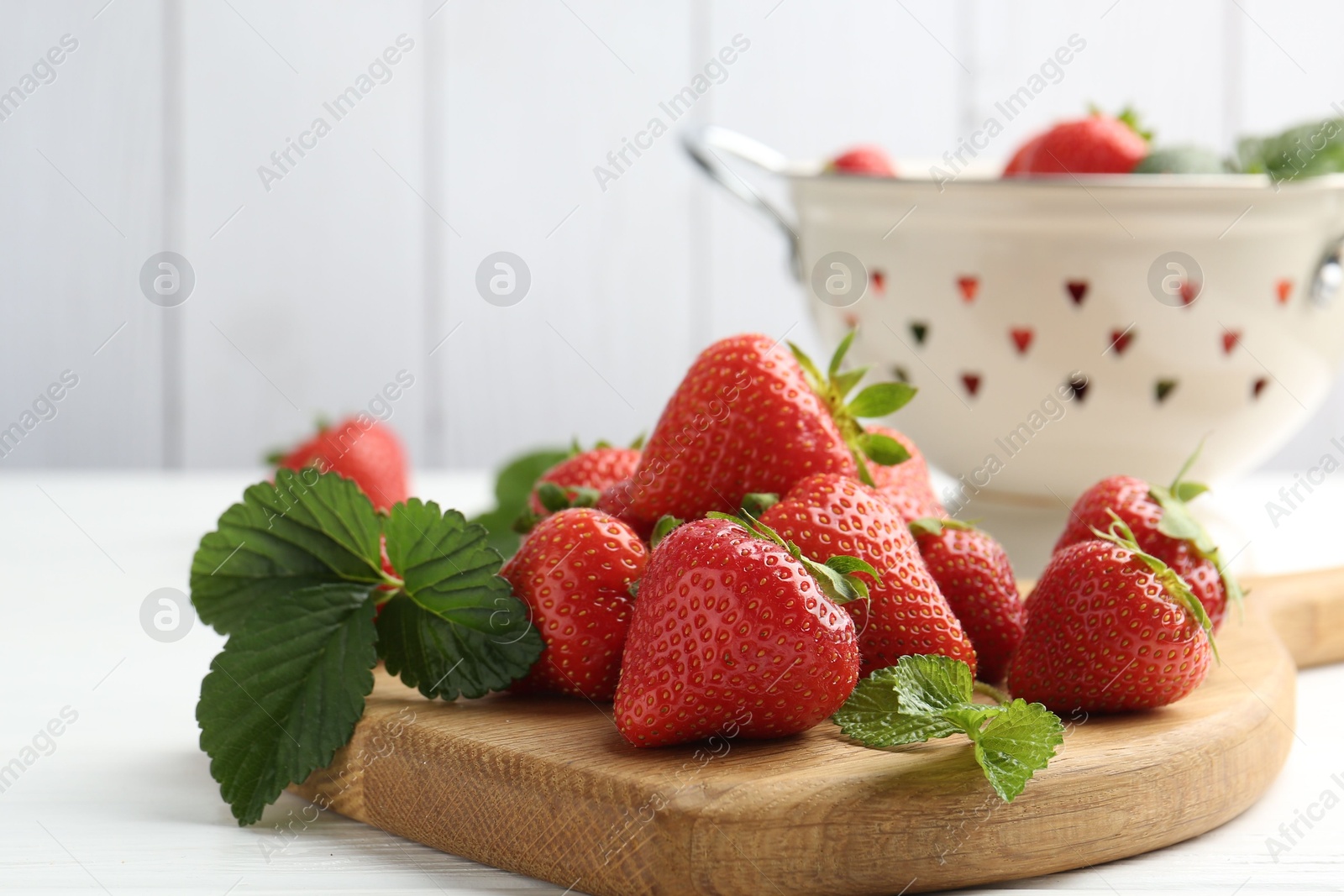 Fresh ripe strawberries and leaves on white wooden table, closeup Photo of Fresh ripe strawberries and leaves on white wooden table, closeup