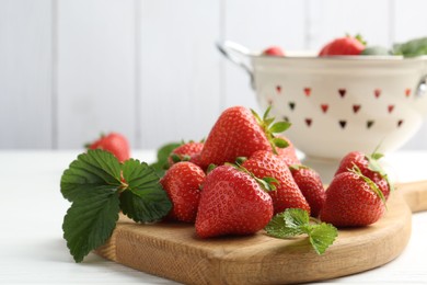 Photo of Fresh ripe strawberries and leaves on white wooden table, closeup