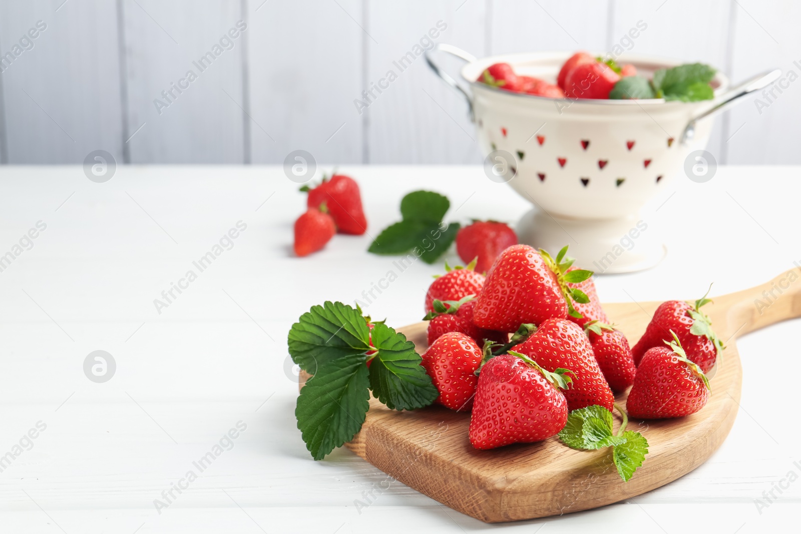 Fresh ripe strawberries and leaves on white wooden table. Space for text Photo of Fresh ripe strawberries and leaves on white wooden table. Space for text