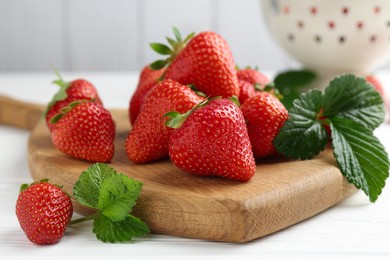 Photo of Fresh ripe strawberries and leaves on white wooden table, closeup