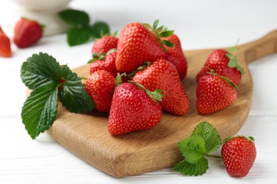 Photo of Fresh ripe strawberries and leaves on white wooden table, closeup