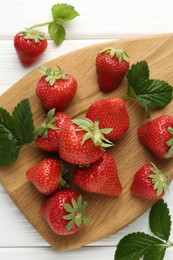 Photo of Fresh ripe strawberries and leaves on white wooden table, flat lay