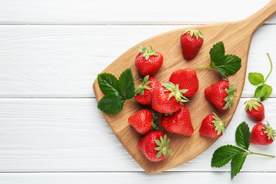 Photo of Fresh ripe strawberries and leaves on white wooden table, top view. Space for text