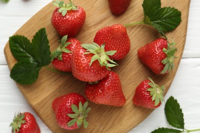 Photo of Fresh ripe strawberries and leaves on white wooden table, top view