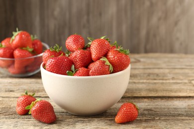 Photo of Fresh ripe strawberries in bowl on wooden table, closeup. Space for text