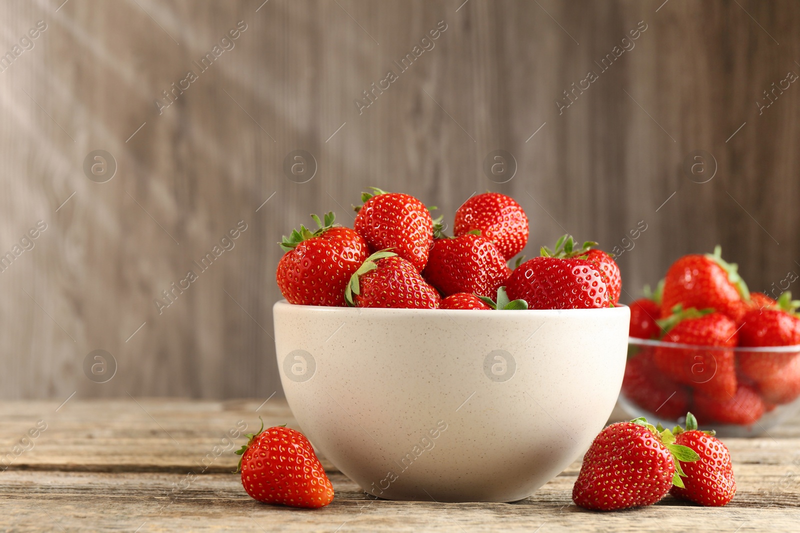 Fresh ripe strawberries in bowl on wooden table, closeup. Space for text Photo of Fresh ripe strawberries in bowl on wooden table, closeup. Space for text