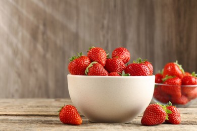 Photo of Fresh ripe strawberries in bowl on wooden table, closeup. Space for text