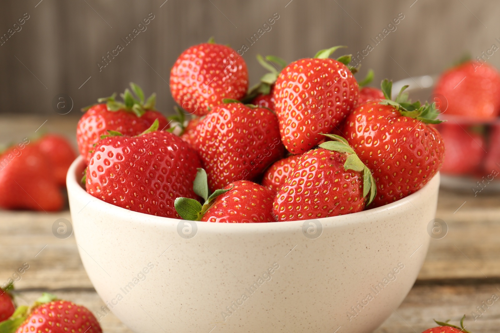Fresh ripe strawberries in bowl on wooden table, closeup Photo of Fresh ripe strawberries in bowl on wooden table, closeup