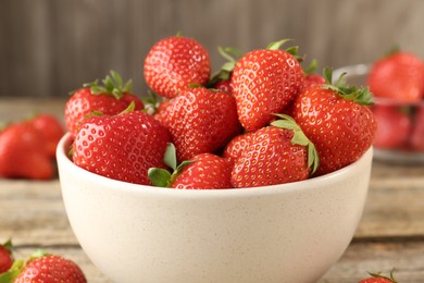 Photo of Fresh ripe strawberries in bowl on wooden table, closeup