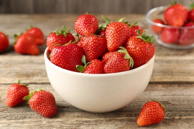 Photo of Fresh ripe strawberries in bowl on wooden table, closeup