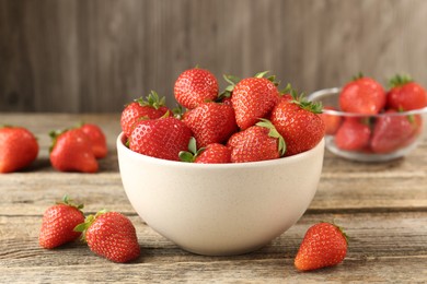 Photo of Fresh ripe strawberries in bowl on wooden table, closeup
