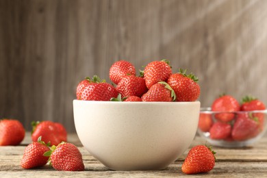Photo of Fresh ripe strawberries in bowl on wooden table, closeup