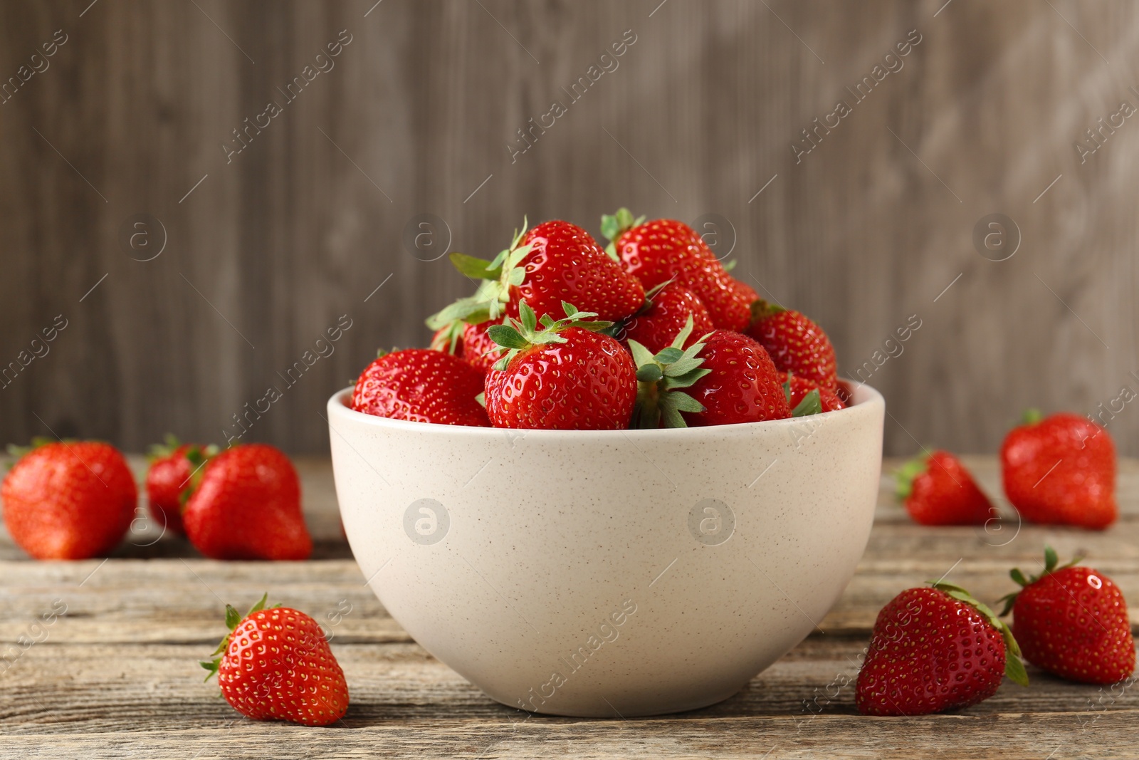 Fresh ripe strawberries in bowl on wooden table, closeup Photo of Fresh ripe strawberries in bowl on wooden table, closeup