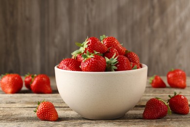 Photo of Fresh ripe strawberries in bowl on wooden table, closeup