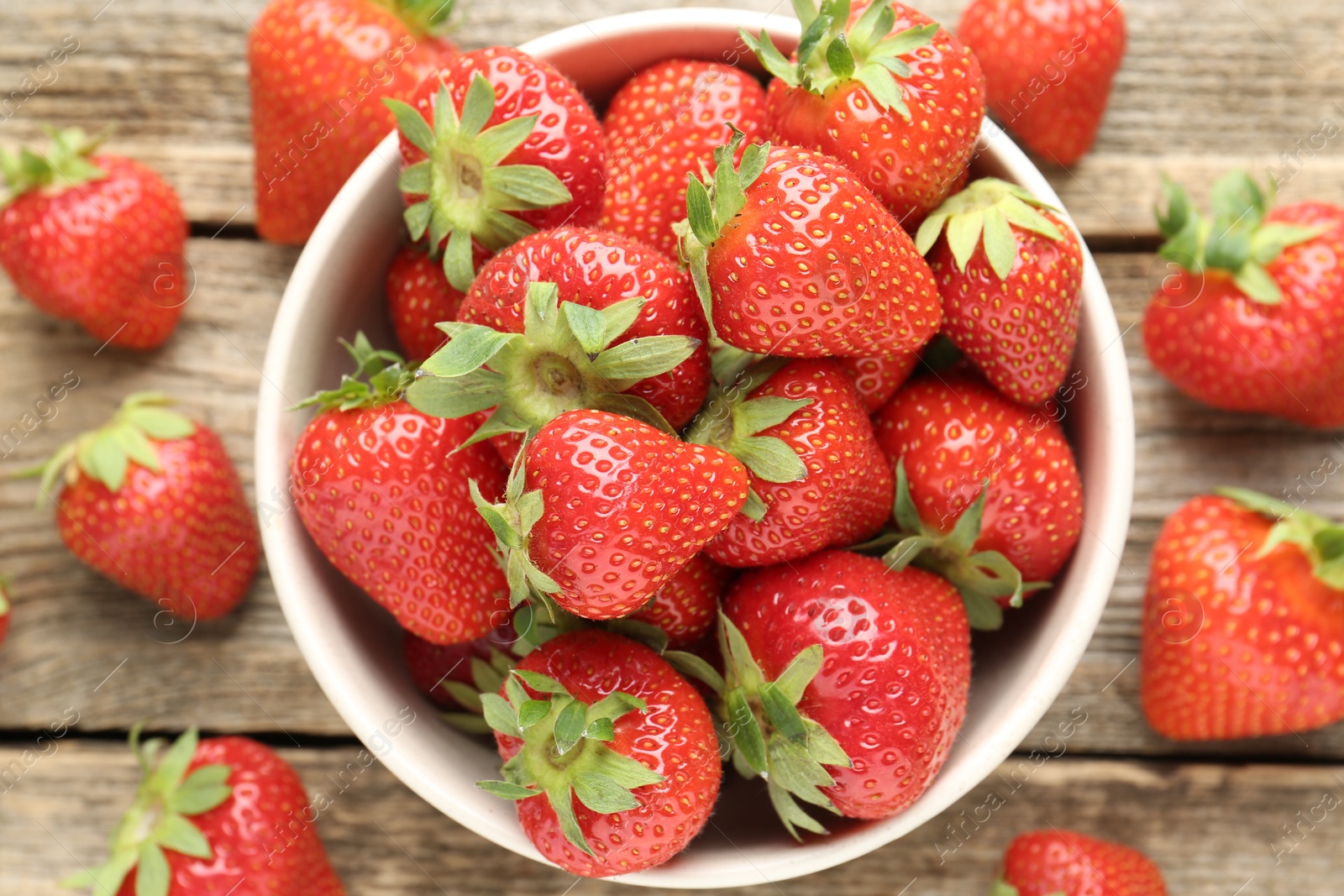 Fresh ripe strawberries in bowl on wooden table, flat lay Photo of Fresh ripe strawberries in bowl on wooden table, flat lay