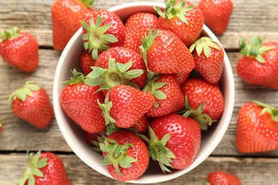 Photo of Fresh ripe strawberries in bowl on wooden table, flat lay