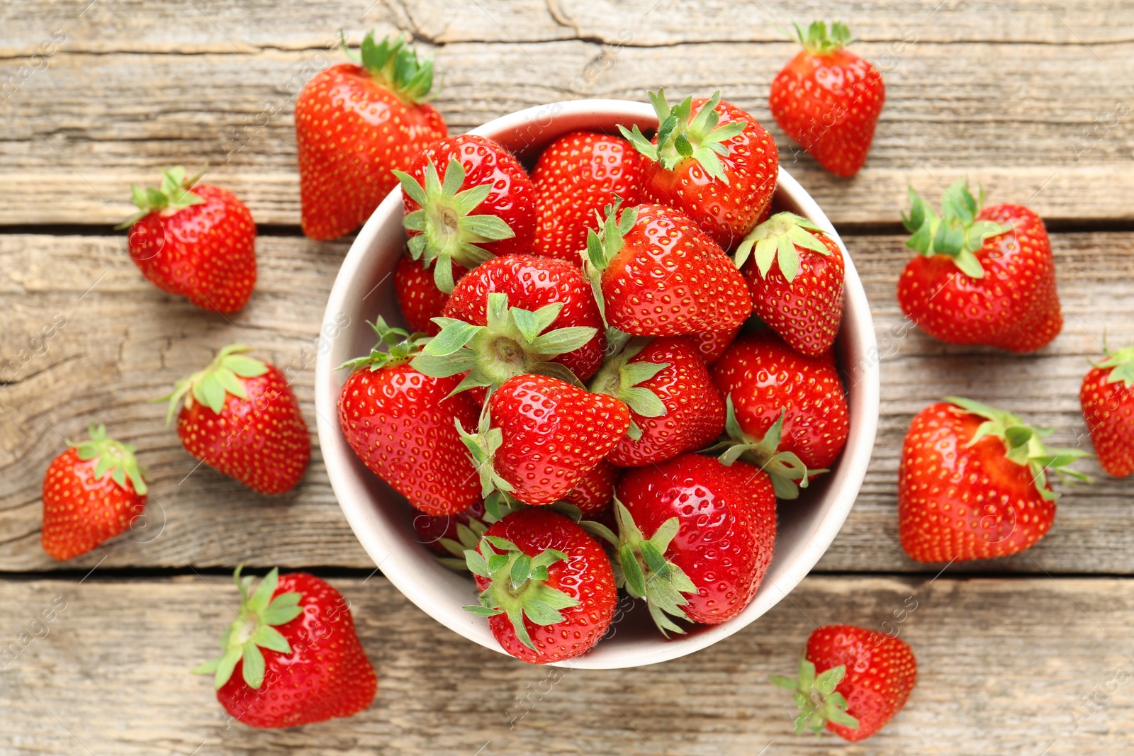 Fresh ripe strawberries in bowl on wooden table, flat lay Photo of Fresh ripe strawberries in bowl on wooden table, flat lay