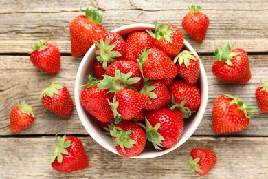 Photo of Fresh ripe strawberries in bowl on wooden table, flat lay