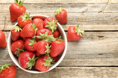 Photo of Fresh ripe strawberries in bowl on wooden table, flat lay. Space for text