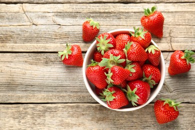 Photo of Fresh ripe strawberries in bowl on wooden table, flat lay. Space for text