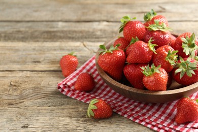 Photo of Fresh ripe strawberries in bowl on wooden table, closeup. Space for text