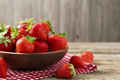 Photo of Fresh ripe strawberries in bowl on wooden table, closeup. Space for text