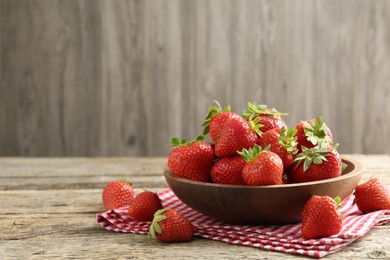 Photo of Fresh ripe strawberries in bowl on wooden table, closeup. Space for text