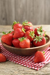 Photo of Fresh ripe strawberries in bowl on wooden table, closeup