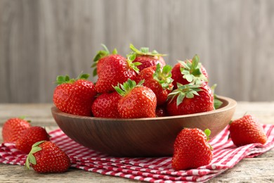 Photo of Fresh ripe strawberries in bowl on wooden table, closeup
