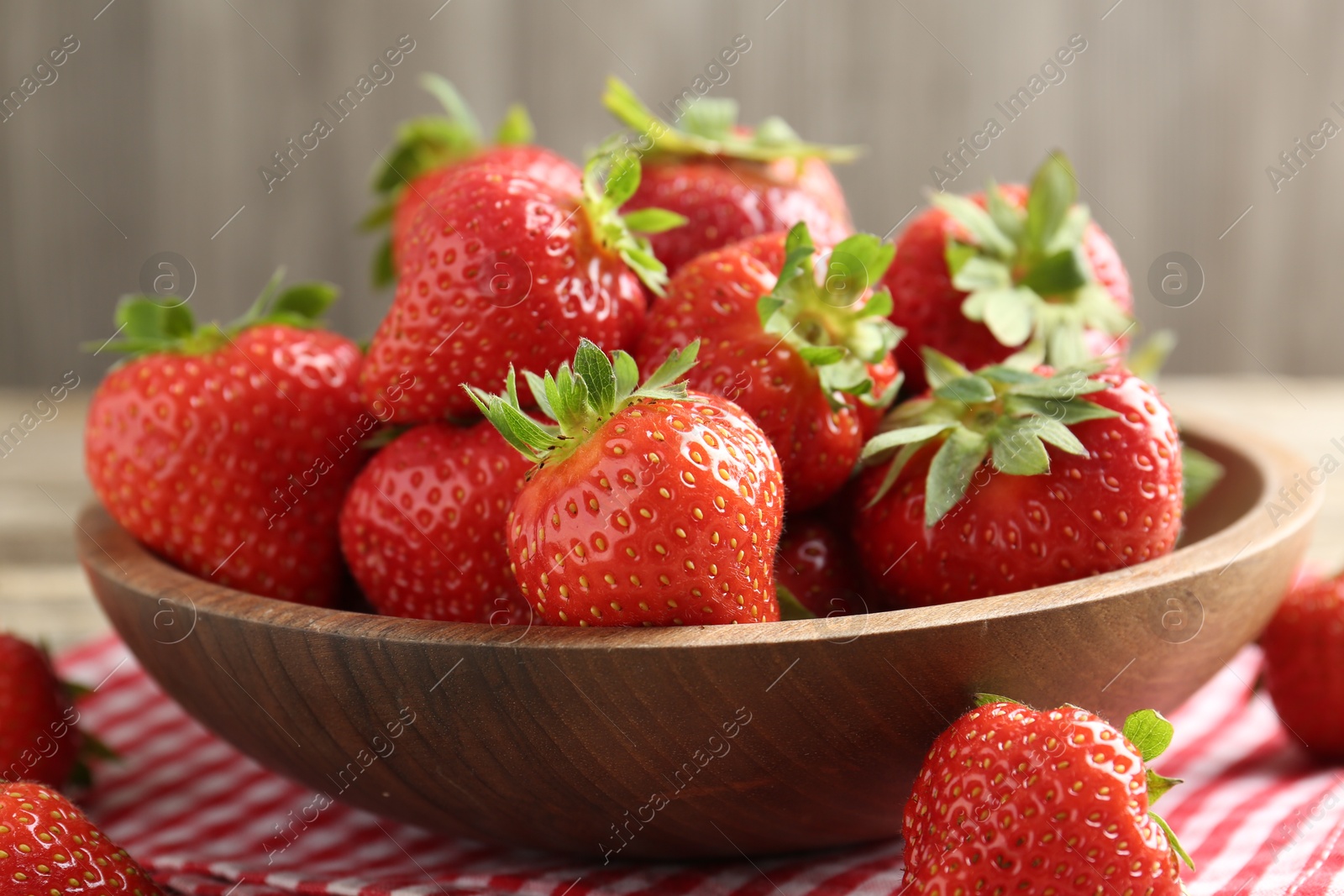 Fresh ripe strawberries in bowl on wooden table, closeup Photo of Fresh ripe strawberries in bowl on wooden table, closeup