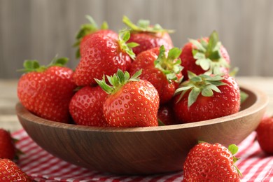 Photo of Fresh ripe strawberries in bowl on wooden table, closeup