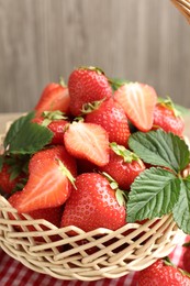 Photo of Delicious ripe strawberries in wicker basket on table, closeup