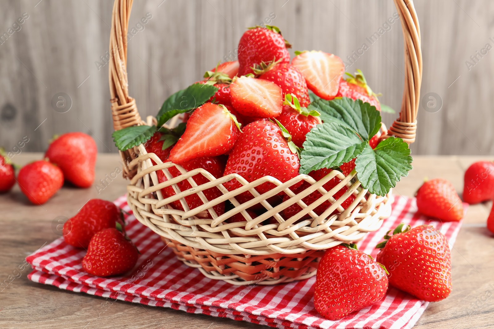 Delicious ripe strawberries in wicker basket on wooden table, closeup Photo of Delicious ripe strawberries in wicker basket on wooden table, closeup