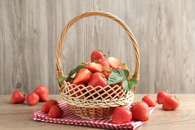 Photo of Delicious ripe strawberries in wicker basket on wooden table