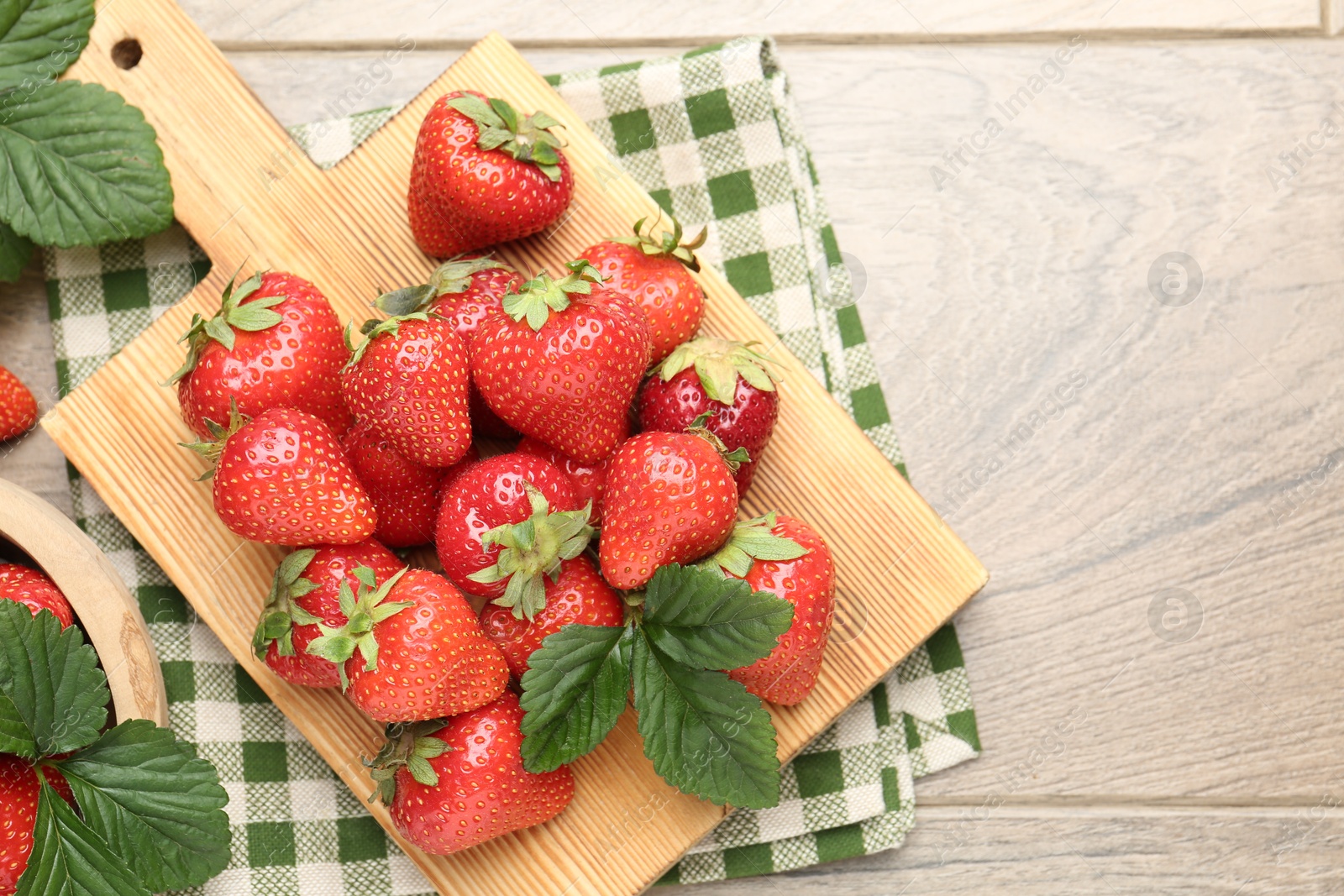 Delicious ripe strawberries and green leaves on wooden table, flat lay. Space for text Photo of Delicious ripe strawberries and green leaves on wooden table, flat lay. Space for text