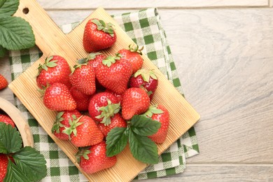 Photo of Delicious ripe strawberries and green leaves on wooden table, flat lay. Space for text